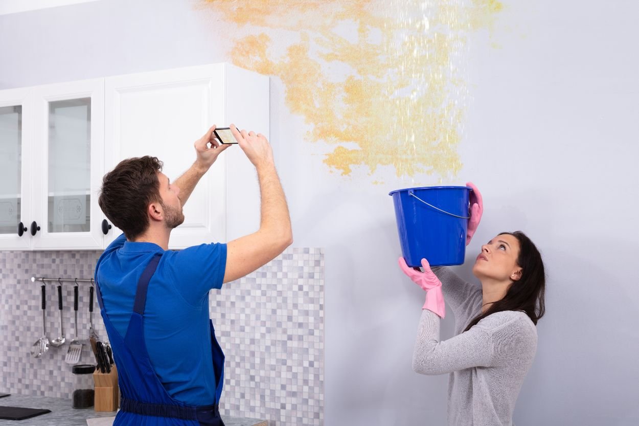 A man and woman scrub a yellow-painted kitchen, illustrating a water damage restoration service in Las Vegas, NV.