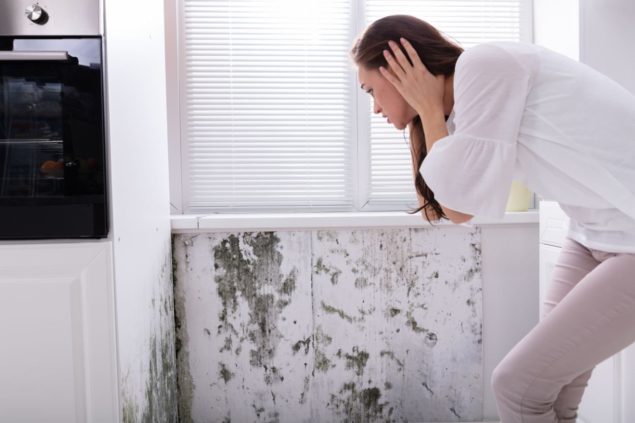 A woman stands in a kitchen with visible mold on the wall, highlighting the need for crawl space mold removal in Las Vegas, NV.