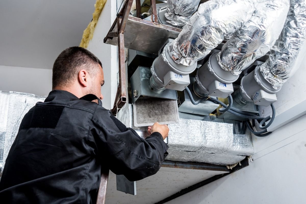 A man in a black shirt operates a furnace, demonstrating the use of UV lights in HVAC systems for improved air quality.
